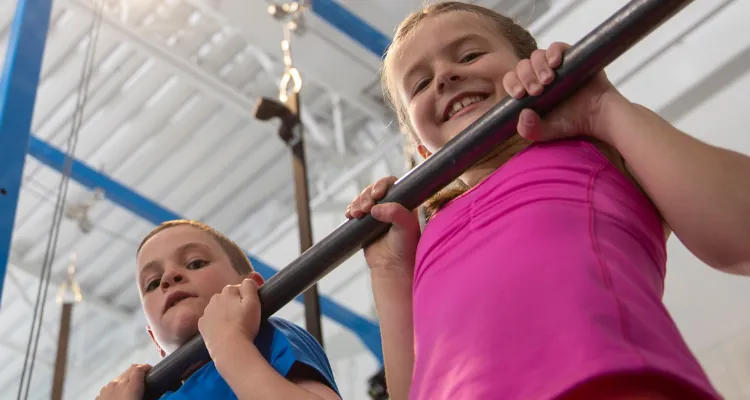 Six year old girl and boy hanging from bar